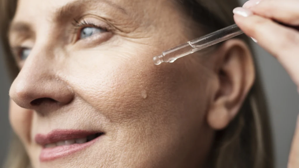 A woman applying a skincare serum to her face, demonstrating a step in the process of how to get rid of acne scars