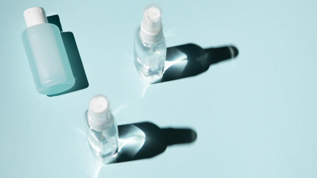 Three skincare bottles with pure Acetone, arranged on a light blue
background, casting distinct shadows.